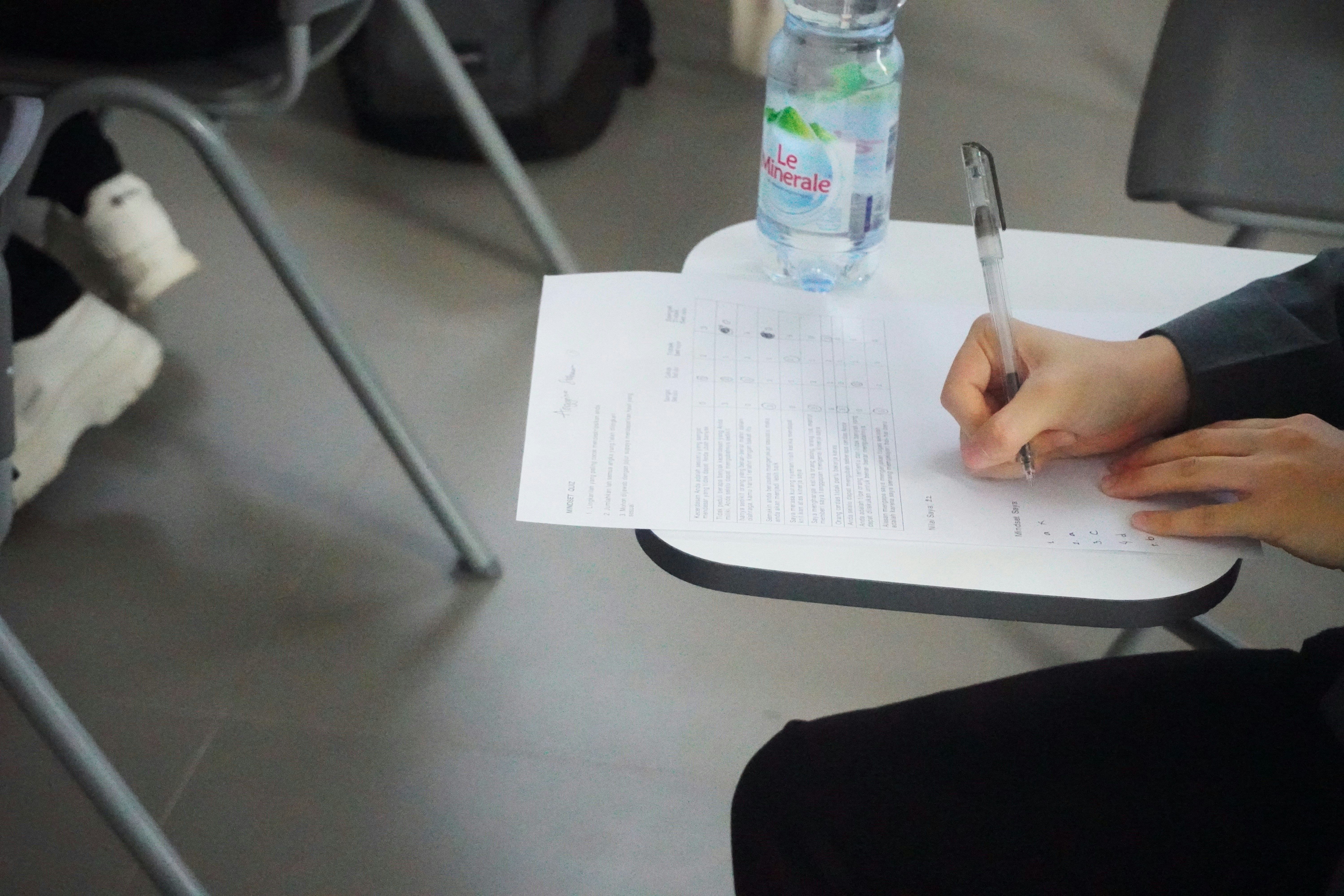 Candidate writing a test paper on a small table 